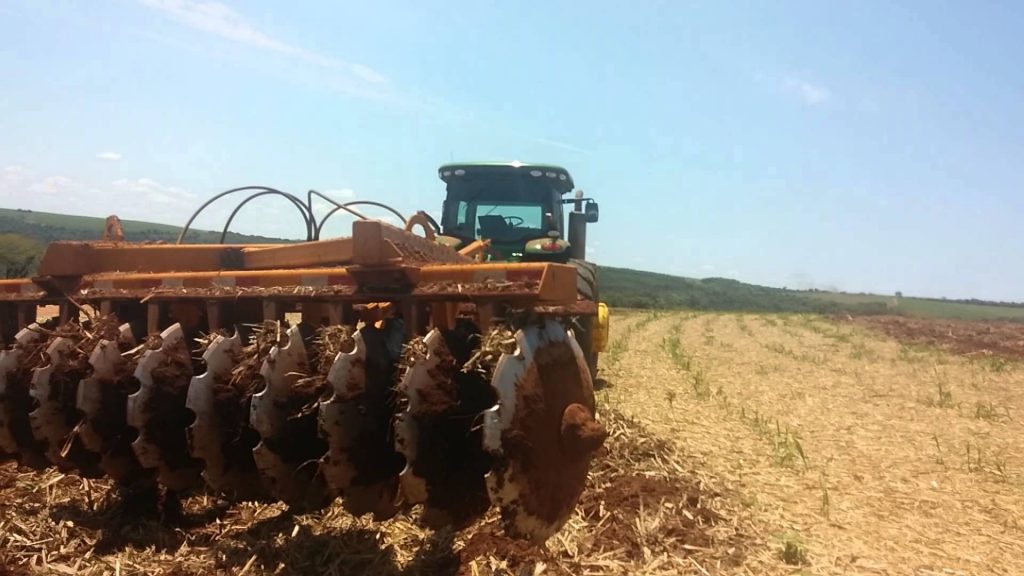 Sistema de plantio e seu tratamento com o solo. A imagem mostra uma máquina de discos grossos descompactando um solo.